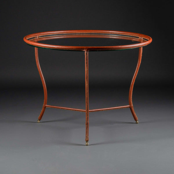 Jacques ADNET (1900-1984) Petite table basse ronde tripode en cuir sellier surpiqué marron, vers 1950.