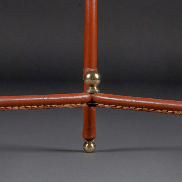 Jacques ADNET (1900-1984) Petite table basse ronde tripode en cuir sellier surpiqué marron, vers 1950.
